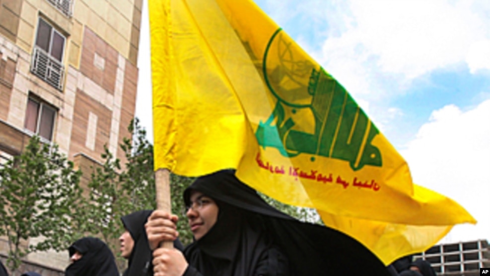 FILE - A woman holds a flag of the Lebanese militant group Hezbollah. The Lebanese-based group issued a statement Friday on a Beirut television channel saying Badreddine was killed in an Israeli airstrike. 