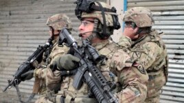 U.S. soldiers stand guard at the scene of a suicide attack in Kabul, Afghanistan, Feb. 27, 2013.