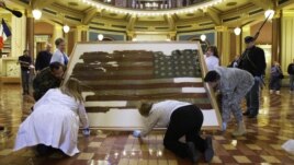 Workers carry the 34-star U.S. national flag of the 15th Iowa Infantry 