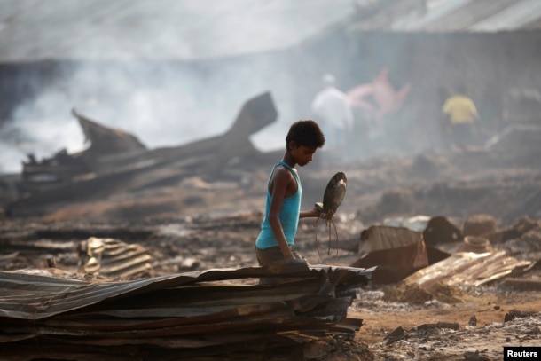 FILE - A boy searches for useful items among the ashes of burned-down dwellings at a camp for internally displaced Rohingya Muslims in Myanmar's western Rakhine state near Sittwe, May 3, 2016.