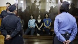 Feminist punk group Pussy Riot members, from left, Yekaterina Samutsevich, Maria Alekhina and Nadezhda Tolokonnikova sit in a glass cage at a courtroom in Moscow, Russia, Aug 17, 2012.