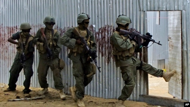 Masked Somali national army (SNA) soldiers search through homes for al-Shabaab fighters, during an operation in Ealsha Biyaha, Somalia, Saturday, June, 2, 2012.