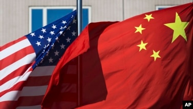 FILE - The flags of the United States and China flutter in winds outside a hotel in Beijing.