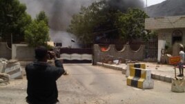 A man takes a photo of smoke rising from the site of an attack on the Political Security Agency building, the headquarters of the Yemeni intelligence services in the southern provinces, in the southern Yemeni city of Aden August 18, 2012. 