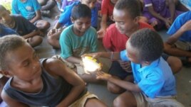 In a remote village in Fiji, children get a chance to learn about renewable energy as part of their curriculum and try out a new solar powered lamp donated to the school. (Energy for All)