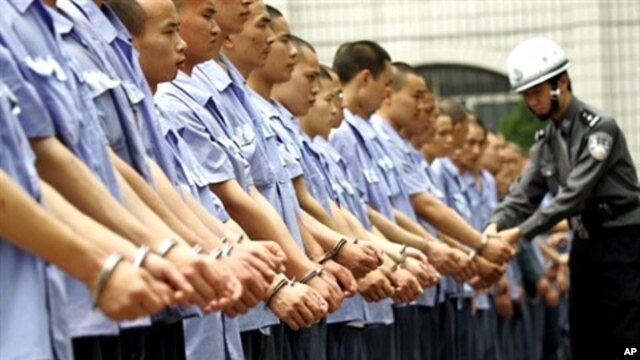 Guard checks handcuffs on group of prisoners in Chongqing (file photo)