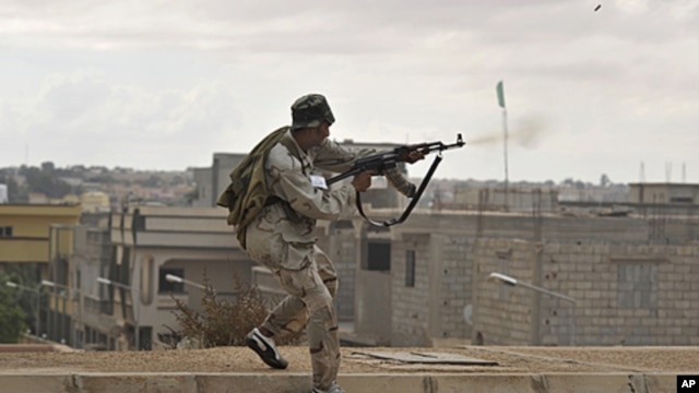 A Libyan revolutionary fighter fires his machine gun while attacking pro-Gadhafi forces on the western side of Sirte, Libya, October 13, 2011.