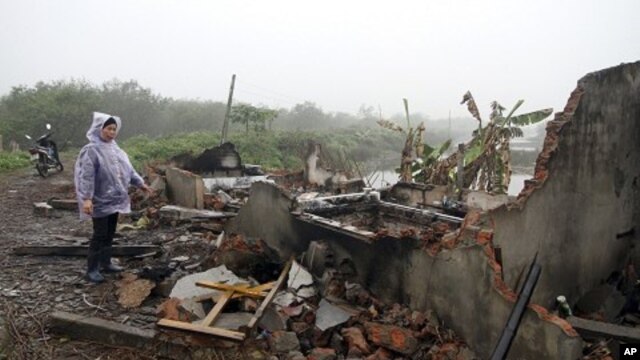 段文旺的妻子2012年2月4日站在他们被摧毁的房屋的瓦砾旁