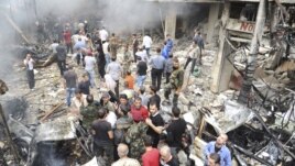 A crowd gathers in front of a building and car damaged after a bomb explosion in the Mezzeh 86 area in Damascus, in this handout photograph released by Syria's national news agency SANA, November 5, 2012. 