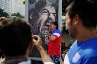 Fans take pictures with a Luis Suarez poster in Rio.