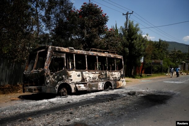 Men walk past a bus that was torched during protests in the town of Sebeta, Oromia region, Ethiopia, Oct. 8, 2016.