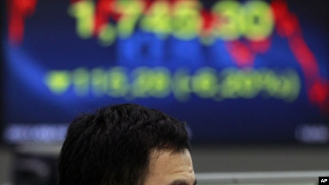 A currency trader reacts as he looks at the monitors at the foreign exchange dealing room of the Korea Exchange Bank headquarters in Seoul, South Korea, August 19, 2011