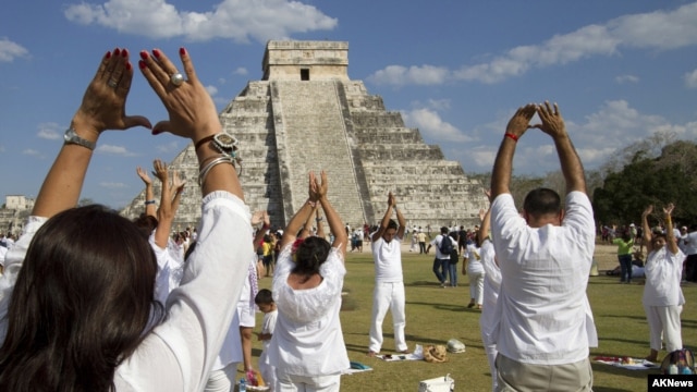 People raise their arms towards the sun while standing in front of the Kukulcan pyramid in Chichen Itza March 20, 2011.