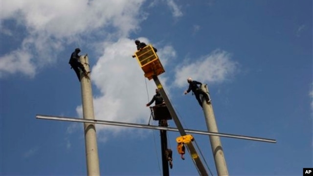 Afghans work on the construction of electricity poles, in the Robat-e-Sangi district, Herat province, west of Kabul, March 28, 2010.