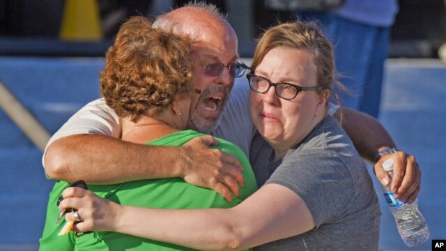 Una familia se abraza desesperada en las afueras del complejo de cines en Aurora, donde buscaban frenéticamente a su hijo de 27 años.
