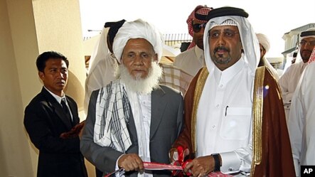 Qatari Assistant Minister for Foreign Affairs Ali bin Fahd al-Hajri (r) and Jan Mohammad Madani, (l) one of the Taliban officials cut the ribbon at the official opening ceremony of a Taliban office in Doha, Qatar,  June 18, 2013. 