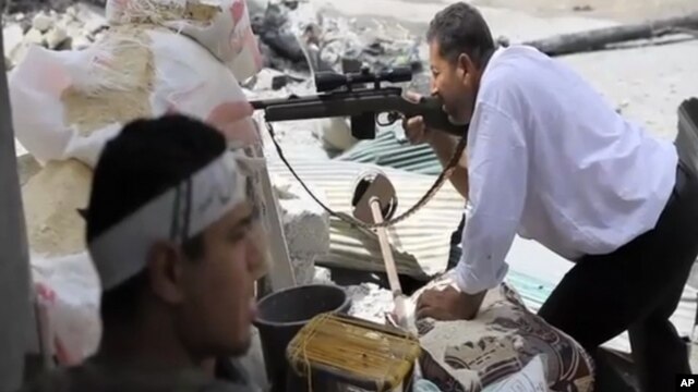 In this image made from video and accessed Saturday, Sept. 1, 2012, a Free Syrian Army fighter takes cover as another fighter fires at Syrian Army positions in Aleppo.