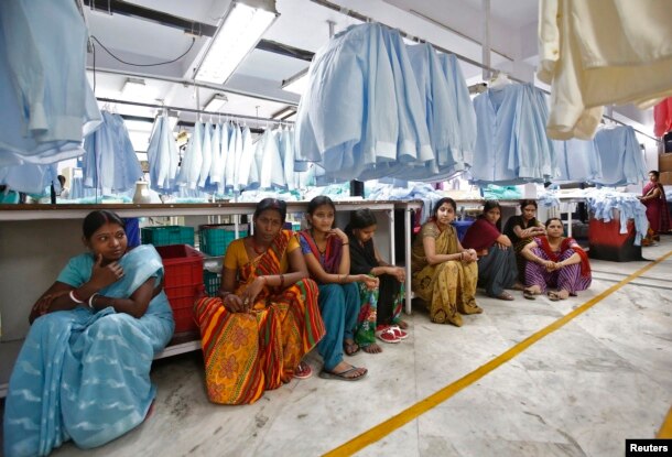 FILE - Employees sit during their lunch time inside a textile mill in India, April 16, 2014.
