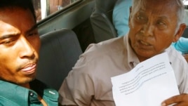 Chum Mey, right, a former S-21 prison survivor, sits in a pickup truck before joining a rally demanding Kem Sokha, vice president of the Cambodia National Rescue Party (CNRP), to apologize for allegedly saying that exhibits at a Khmer Rouge-era genocide museum in Phnom Penh were faked, in front of the party's office, in Phnom Penh, Cambodia, Sunday, June 9, 2013. Cambodia's main opposition party denounced the large demonstration in the capital Sunday, which they said was staged by supporters of Prime Minister Hun Sen to intimidate rivals ahead of July elections. (AP Photo/Heng Sinith)