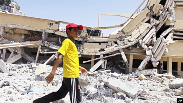 A child walks past the rubble of a university building in Zlitan, Libya, August 4, 2011