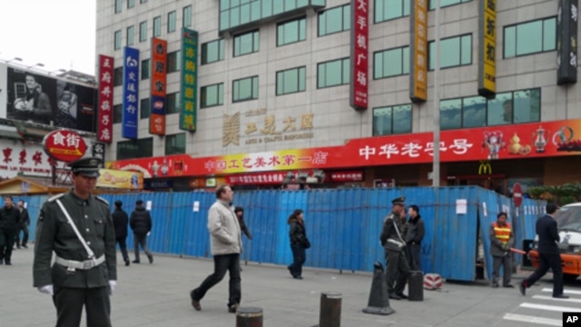 Chinese guards stand at the entrance of the pedestrian Wangfujing area in Beijing. The blue metal barriers are part of a construction site that partially blocks a designated spot for anti-government protests, February 25, 2011.