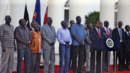 Kenyan President Uhuru Kenyatta, flanked by seven South Sudanese detainees released to his custody, speaks to reporters in Nairobi.