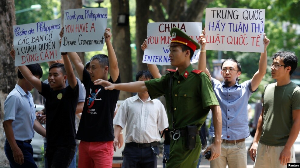 Một nhân viên cảnh sát cố gắng ngăn cản người biểu tình chống Trung Quốc cầm biểu ngữ trong một cuộc biểu tình trước đại sứ quán Philippines tại Hà Nội , Việt Nam, ngày 17 Tháng 7 năm 2016. REUTERS/Kham