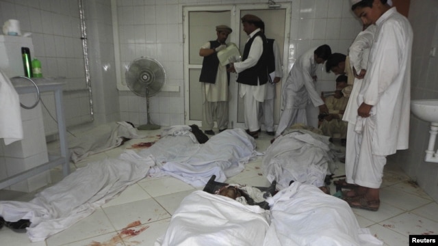 Afghan men stand over the bodies of a suicide bomb blast victims at a hospital in Khost province, June 20, 2012.