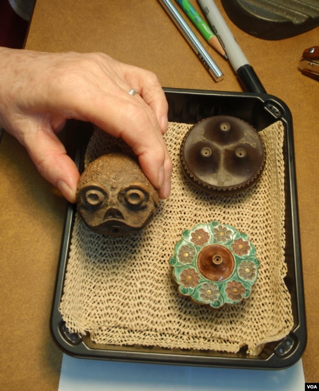 Ceramic opium pipe bowls; the center one has a toad design.(VOA/T. Banse)