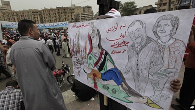 An Egyptian protester carries a banner with drawings depicting ex president Mubarak and reads in Arabic "No forgiveness, our children's blood is not cheap," during a protest at Tahrir Square in Cairo, Egypt, May 27, 2011.