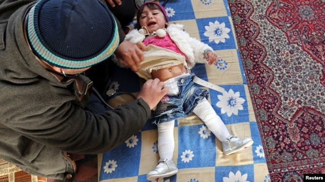 A doctor treats an internally displaced child in a school at a village outside Damascus, January 28, 2013.