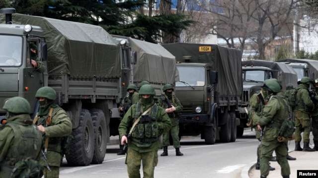 Armed servicemen wait near Russian army vehicles outside a Ukrainian border guard post in the Crimean town of Balaclava, March 1, 2014. 