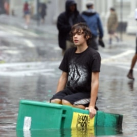 A boy floats on a newspaper box in a flooded street in the Soho section of Manhattan after Hurricane Irene passed over the New York City area August 28, 2011
