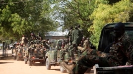South Sudan army soldiers hold their weapons as they ride on a truck in Bor, Dec. 25, 2013.