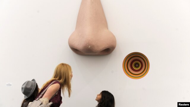 A visitor looks at the sculpture "Vortex Eau De Parfum" by Jim Lampie at the Frieze Art Fair in New York