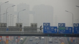 A pedestrian walks across a bridge above a main road on a day with high air pollution in Beijing, June 6, 2012.