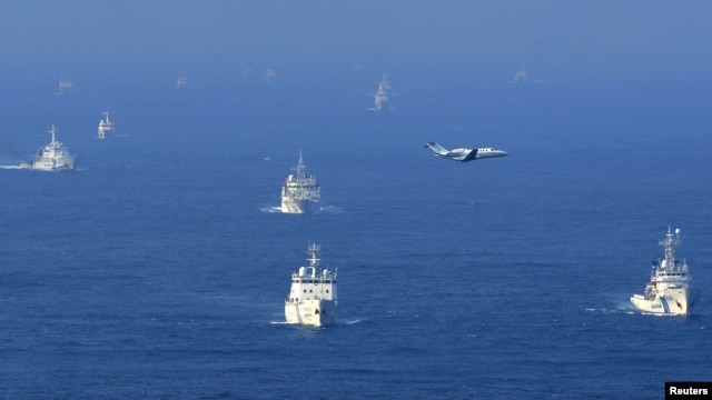 An aerial photo from Kyodo News shows Chinese ocean surveillance, fishery patrol ships and a Japan Coast Guard patrol ship (R and 2nd L) sailing about 27 km (17 miles) west from a group of disputed islands in the East China Sea, September 18, 2012.
