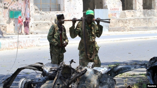 Somali government soldiers look at the wreckage of a mangled car used by a suicide bomber at the scene of a bomb attack next to a tea shop in the suburbs of capital Mogadishu February 27, 2014.
