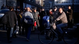 A man cycles past security personnel, and uniformed and plainclothes police, who are standing outside the entrance to a government building where petitioners congregate daily to protest private equity scams, in central Beijing, October 22, 2012.