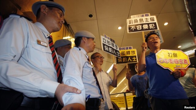 Protesters chant slogans in front of security guards inside building where Japanese Consulate is located in Hong Kong, August 15, 2012.