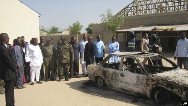 Bystanders gather around a burned car outside the Victory Baptist Church in Maiduguri, Nigeria. Police are blaming members of Boko Haram for the attack on church (File photo - December 25, 2010)