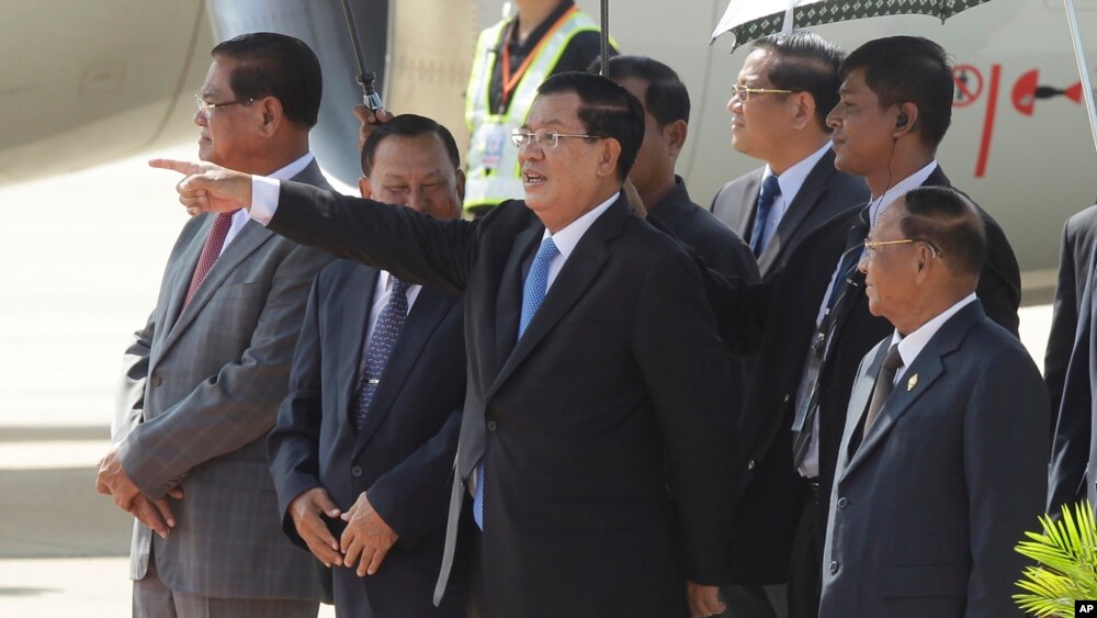 រូបឯកសារ៖ លោកនាយករដ្ឋមន្ត្រី ហ៊ុន សែន (កណ្តាល) ជូនដំណើរព្រះបាទ នរោត្តម សីហមុន្នី នៅអាកាសយានដ្ឋានអន្តរជាតិភ្នំពេញ កាលពីថ្ងៃច័ន្ទ ទី១៩ ខែតុលា ឆ្នាំ២០១៥។ (AP/ហេង ស៊ីនិត)