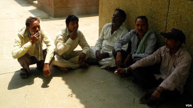 A group of workers relax and smoke during a midday break. (A. Pasricha/VOA)