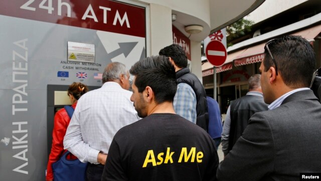A man makes a transaction at an ATM outside a branch of Laiki Bank in Nicosia, March 21, 2013.