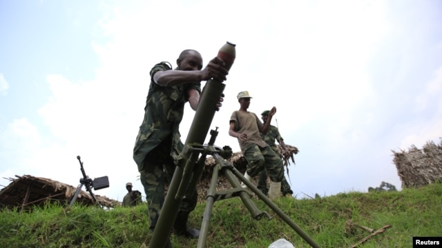  M23 rebel fighter loads an 82mm mortar bomb at their defense position in Karambi, eastern Democratic Republic of Congo (DRC) in north Kivu province, near the border with Uganda, July 12, 2012. 