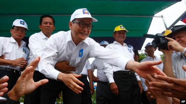 Sam Rainsy, center, president of the Cambodia National Rescue Party, shakes hands with his party supporters during an election campaign at Kampong Speu province, west of Phnom Penh, July 20, 2013. 