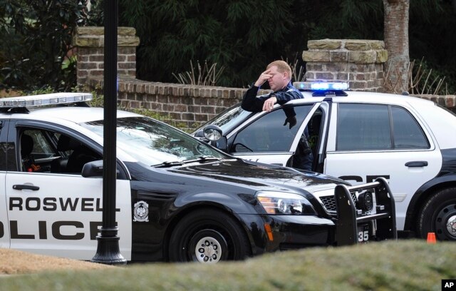 FILE - Roswell Police officers stand guard next to his patrol car in Roswell, Ga., Saturday, Jan. 31, 2015.