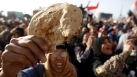 FILE - An Egyptian holds a piece of bread to protest against the high prices of goods in Tahrir Square in Cairo, February 8, 2013. 