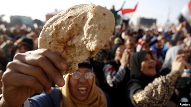 FILE - An Egyptian holds a piece of bread to protest against the high prices of goods in Tahrir Square in Cairo, February 8, 2013. 