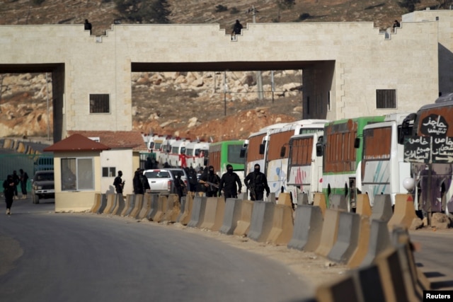 Fighters from a coalition of rebel groups called "Jaish al Fatah", also known as "Army of Fatah" (Conquest Army), secure the area while buses evacuating fighters and civilians from the two besieged Shi'ite towns of al-Foua and Kefraya in the mainly rebel-held northwestern province of Idlib, arrive at the Syrian-Turkish border crossing of Bab al-Hawa, Dec. 28, 2015.